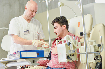Professionnel de santé assistant un jeune patient pendant une session de traitement médical ; illustrant le soutien à la chimiothérapie chez les patients atteints d'un cancer du poumon.
